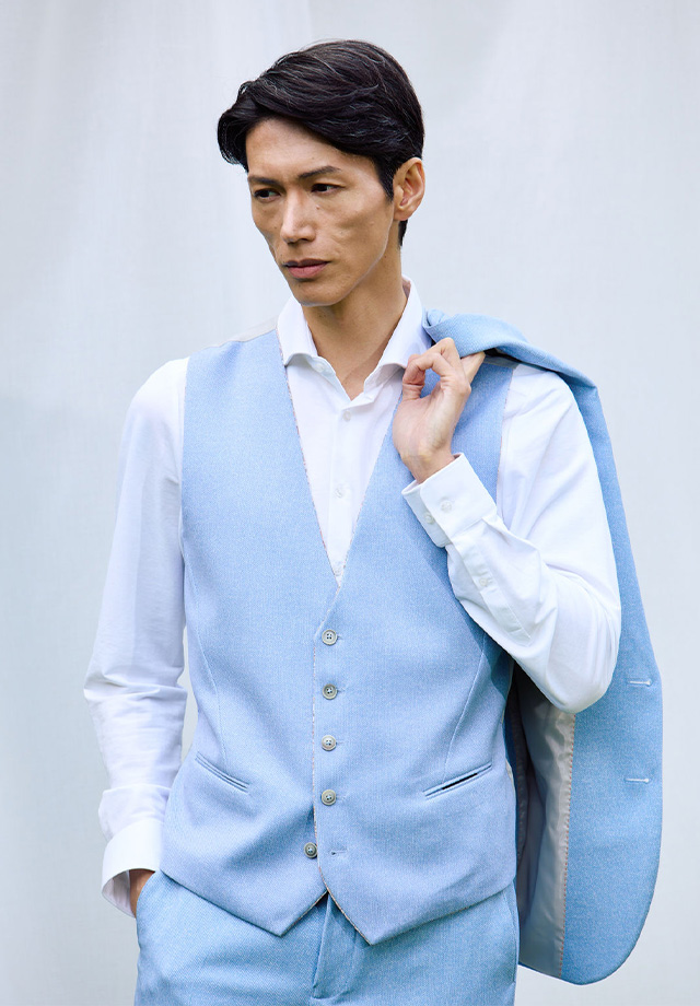 Mann in hellblauer Anzugweste mit passendem Sakko über der Schulter, getragen über weißem Hemd