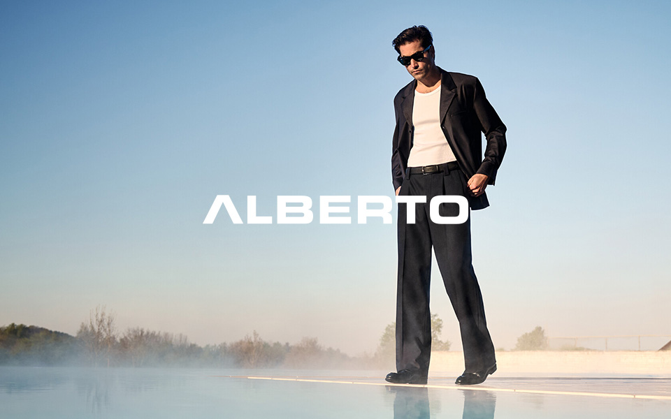 Mann in dunklem Anzug mit weißem T-Shirt und Sonnenbrille am Pool