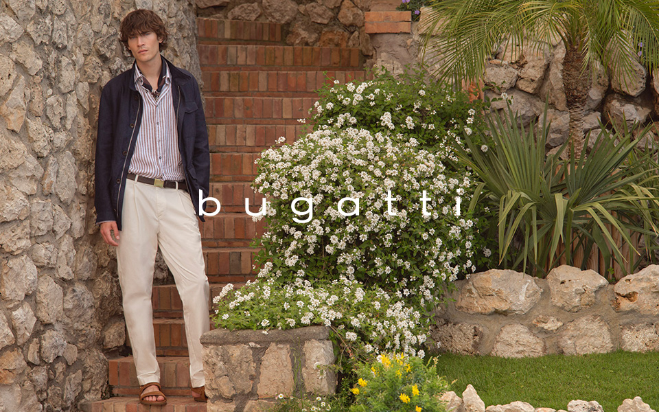 Mann in gestreiftem Freizeithemd mit dunkelblauer Jacke und weißer Hose lässig auf Treppe