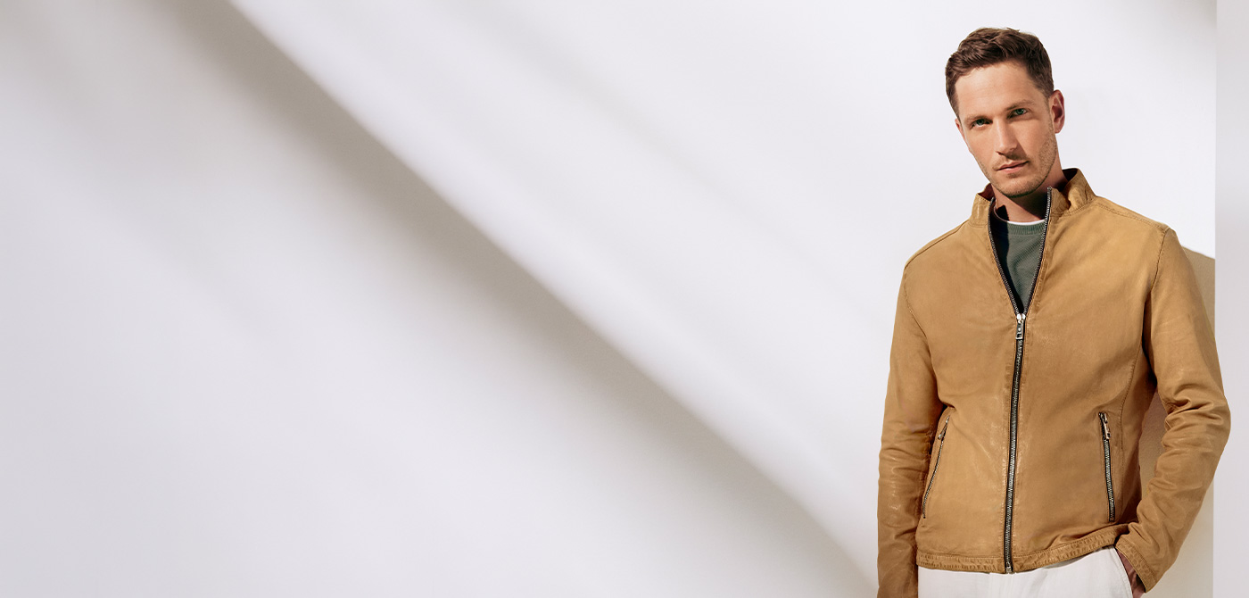 Hellbraune Lederjacke, Reißverschluss, lässig über grünem Pullover getragen