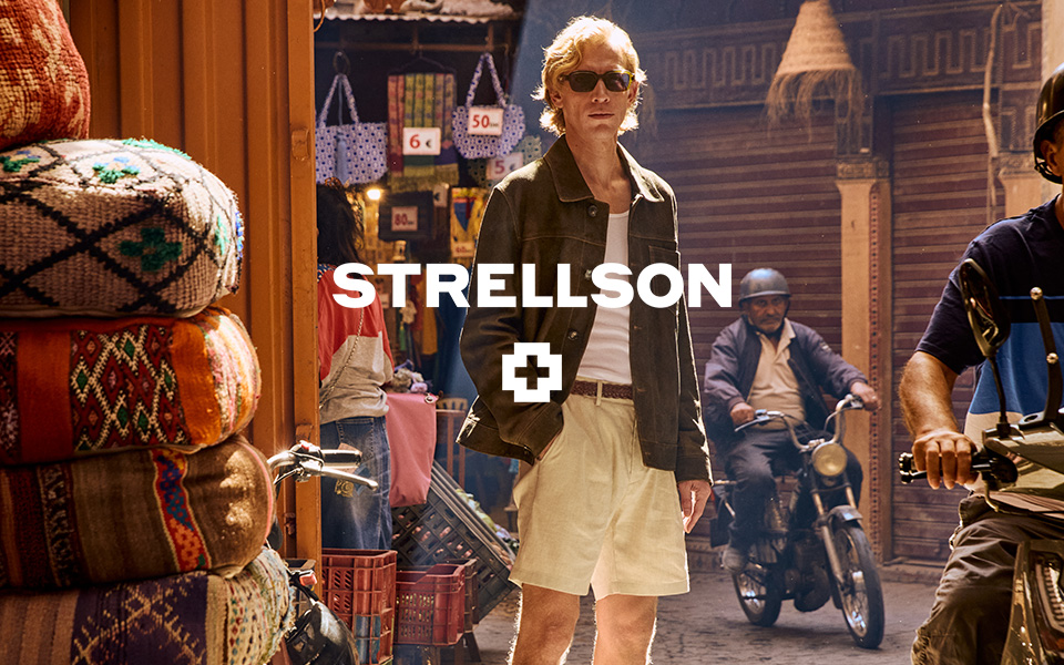 Mann in dunkelbrauner Lederjacke und beiger Shorts auf Markt, lässiger Sommerlook