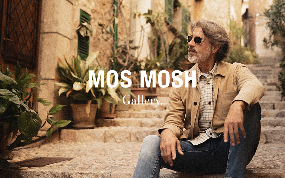 Mann in beiger Jacke mit kariertem Hemd und Jeans sitzt lässig auf Natursteintreppe