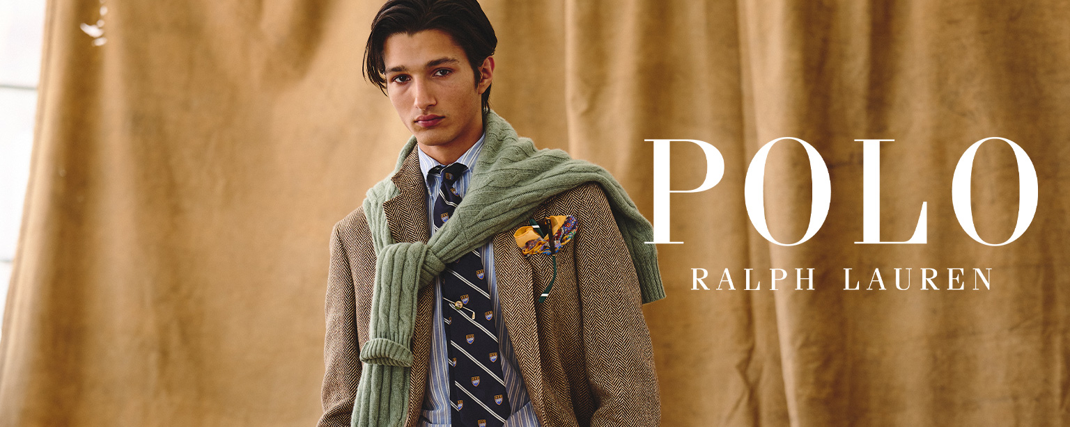 Mann in braunem Hahnentritt-Sakko mit gestreifter Krawatte und grünem Strickpullover, elegant präsentiert