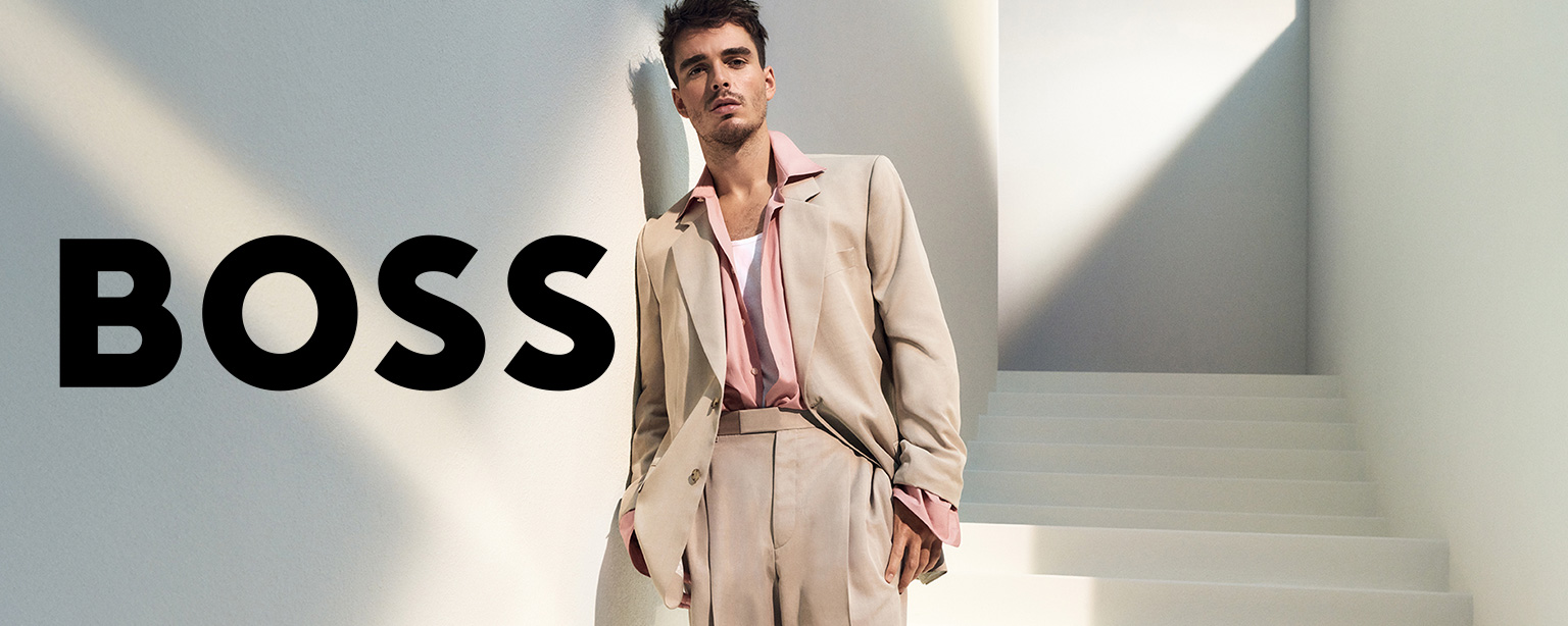 Hellbeiger Anzug aus Wolle, kombiniert mit rosa Hemd, elegant getragen vor minimalistischer Architektur