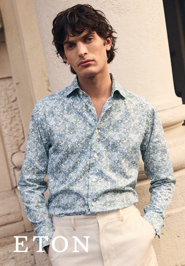 Mann in floral gemustertem, blau-weißem Hemd von Eton dazu eine weiße Hose kombiniert