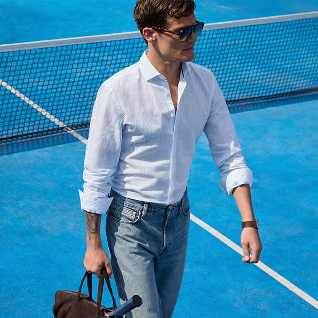 Mann in weißem Langarmhemd mit Jeans auf Tennisplatz