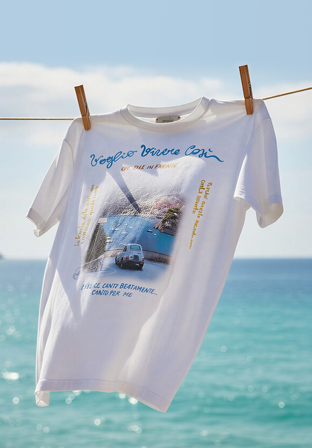 Weißes T-Shirt mit Fotodruck und Schriftzug auf Wäscheleine am Meer