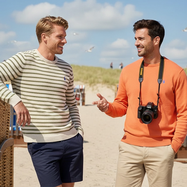 Zwei Männer in gestreiftem Pullover und orangefarbenem Sweatshirt am Strand vor Strandkörben
