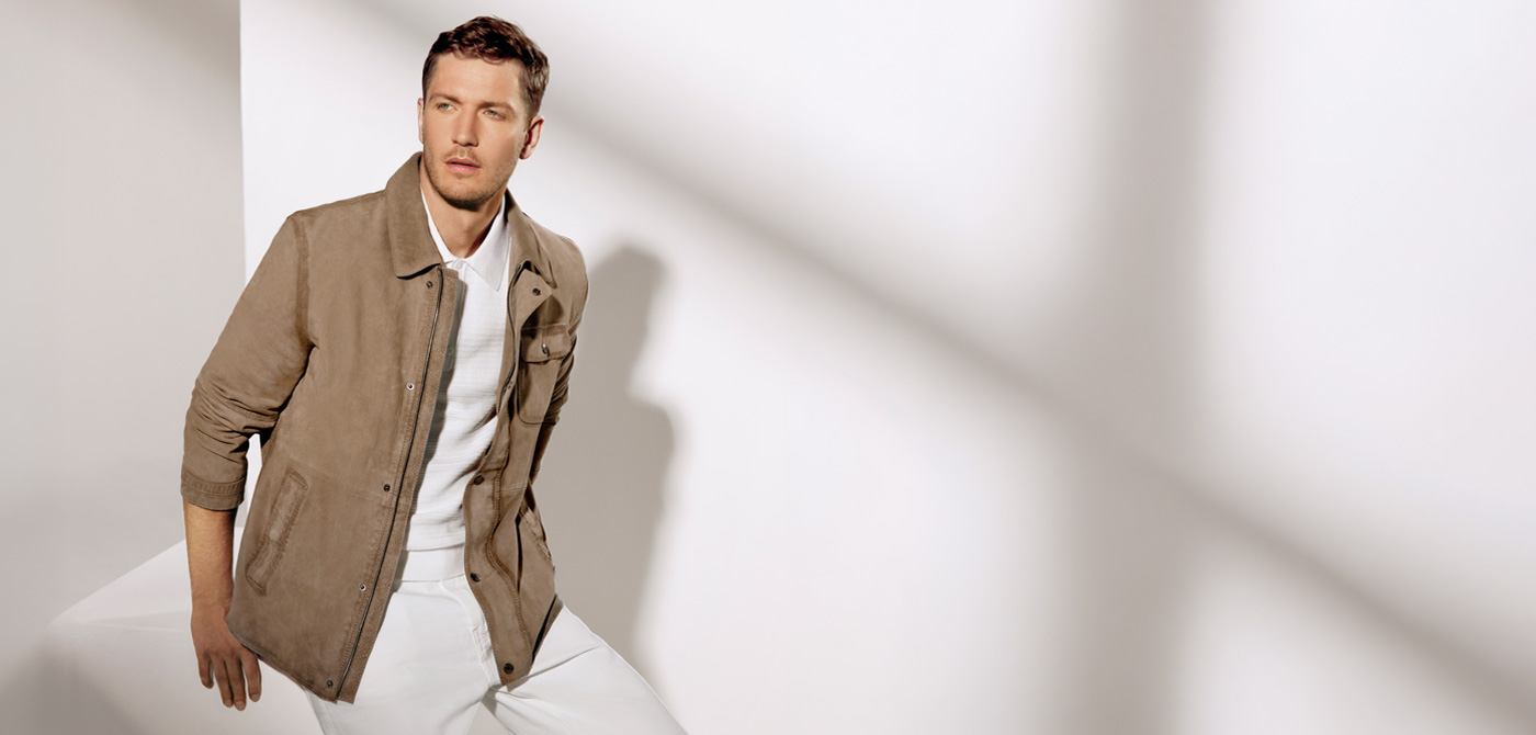 Mann in beiger Wildlederjacke und weißem Poloshirt, elegant präsentiert