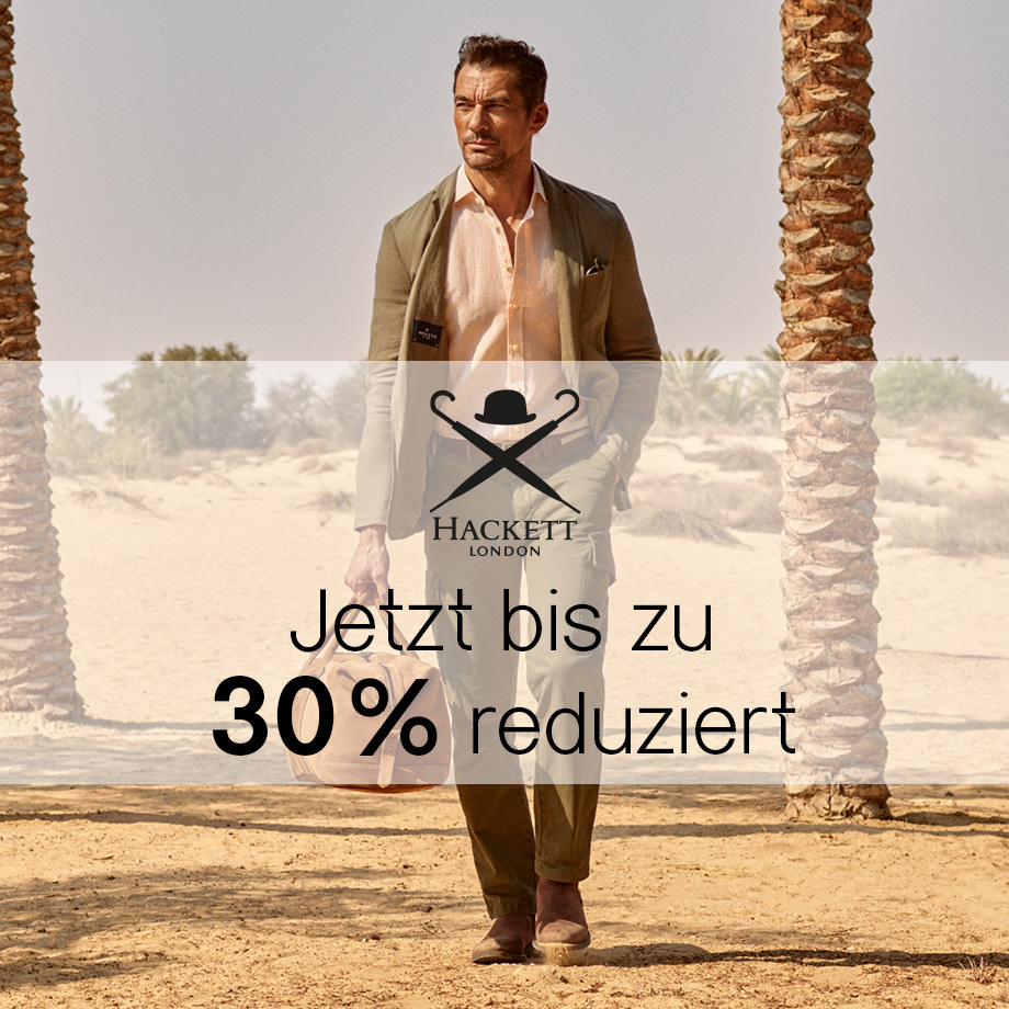 Mann in hellem Blazer mit rosa Hemd und Stoffhose mit Tasche in Wüstenumgebung