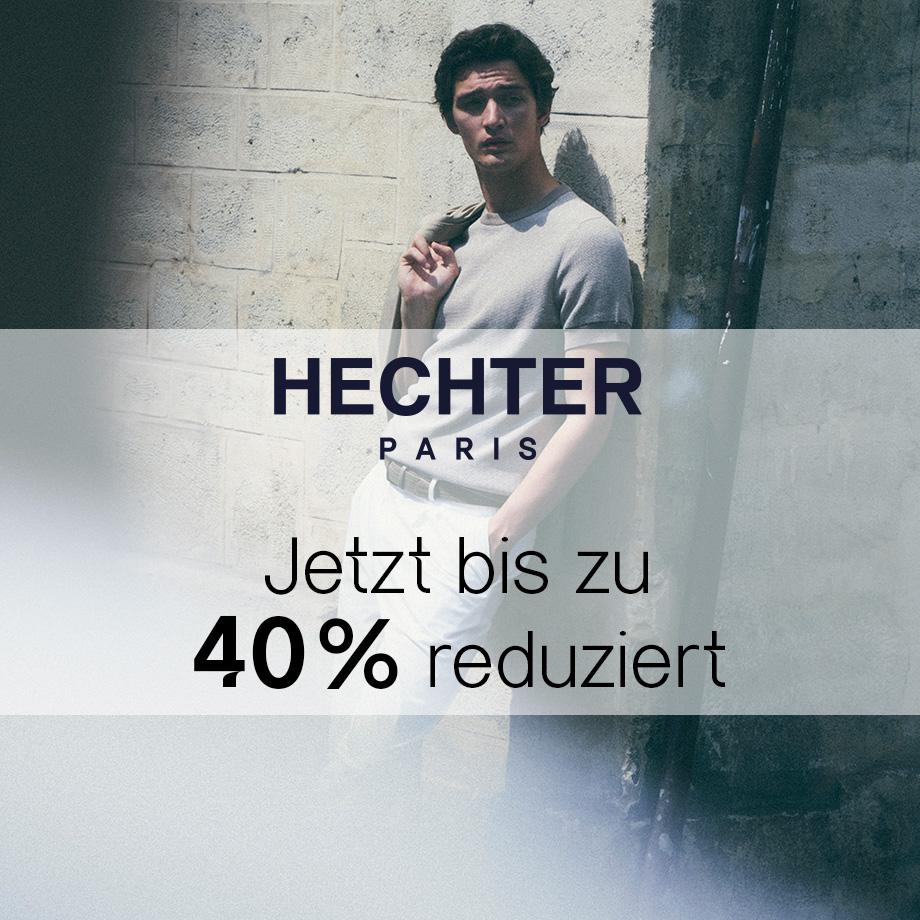 Mann in grauem T-Shirt mit heller Hose, lässig an Wand gelehnt
