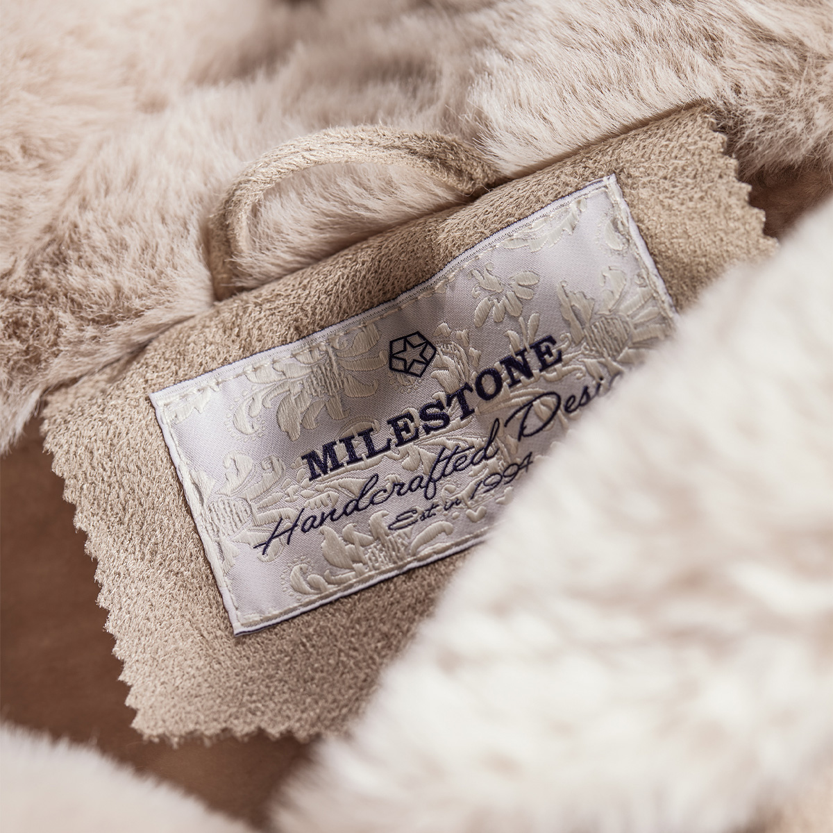 Beiges Innenfutter einer Herrenjacke mit aufgesticktem Logo, hochwertige Verarbeitung