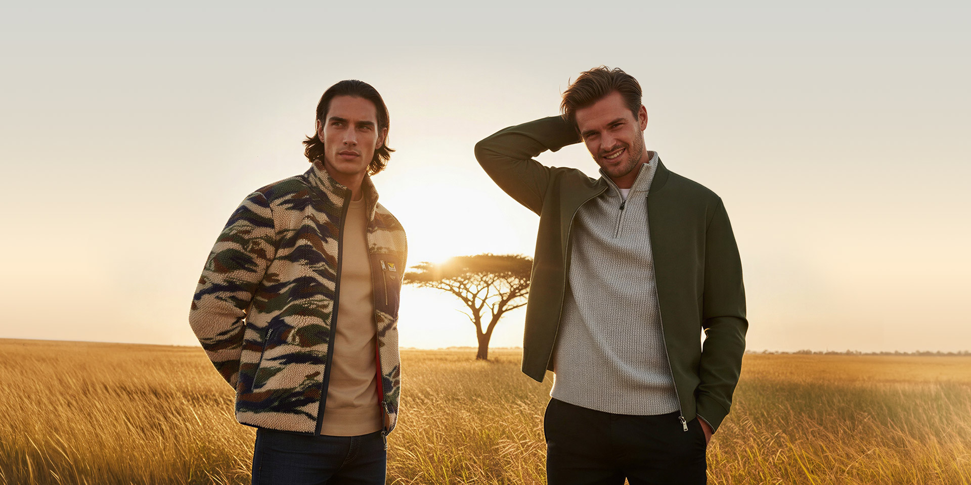 Männer in Outdoor-Jacken, links Camouflage-Muster, rechts khakifarben, in Savannenlandschaft stehend