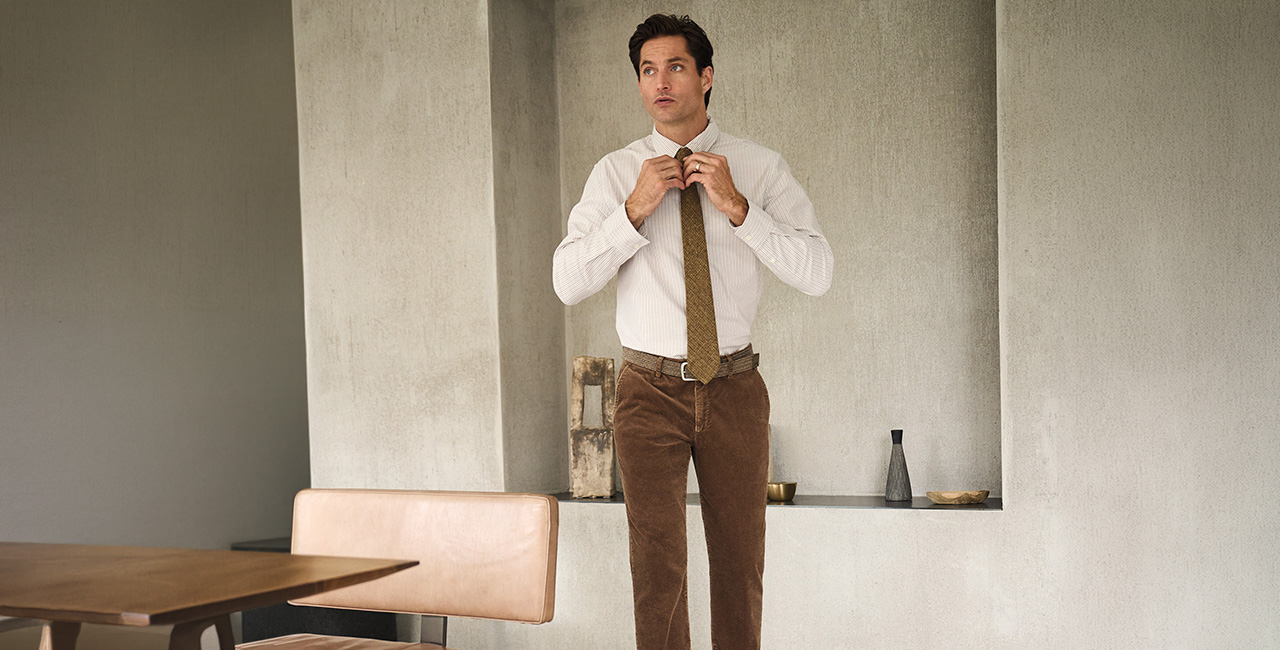 Mann in beige-gestreiftem Business-Hemd mit brauner Krawatte, Bürohintergrund