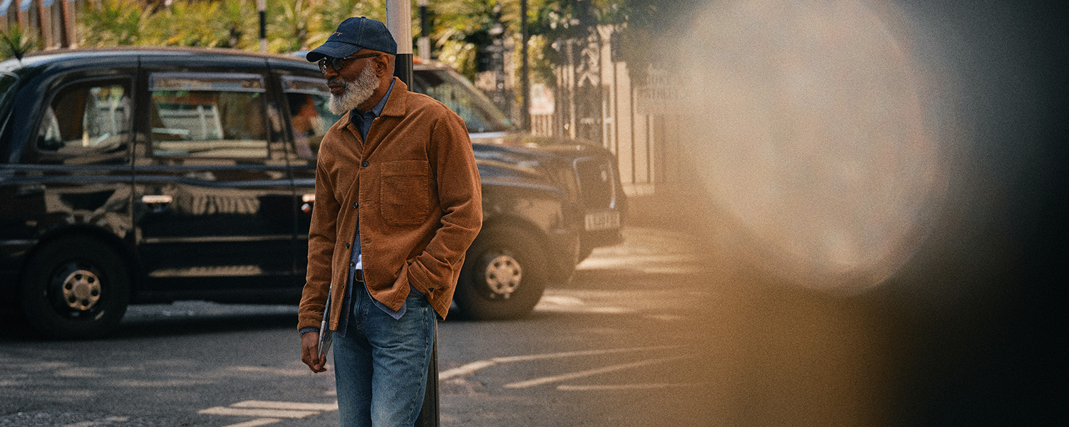 Mann in brauner Cordjacke und Jeans auf Straße, lässig unterwegs