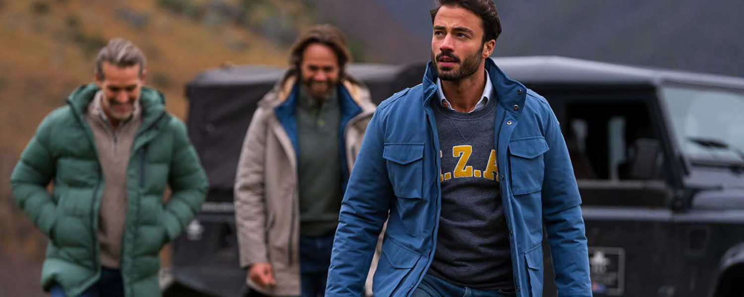 Mann in blauer Übergangsjacke über grauem Pullover, lässig im Freien getragen