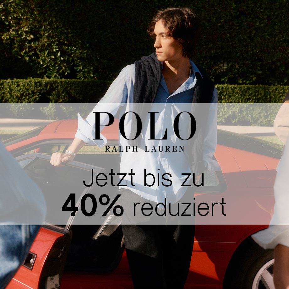 Mann in hellblauem Business-Hemd mit Strickjacke über den Schultern vor rotem Auto