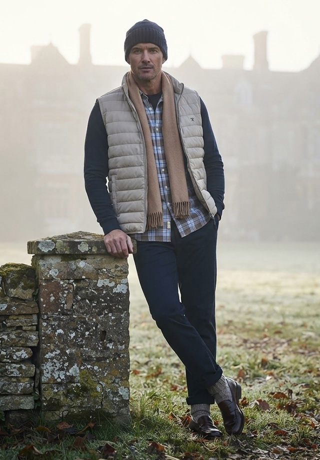 Mann in kariertem Hemd mit beiger Steppweste draußen, Herbstlook