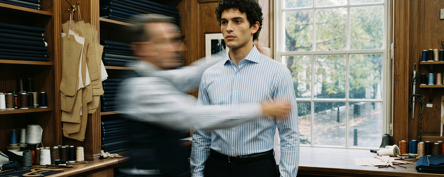 Mann in hellblauem Business-Hemd mit feinen Längsstreifen und schwarzer Anzughose in Schneiderei