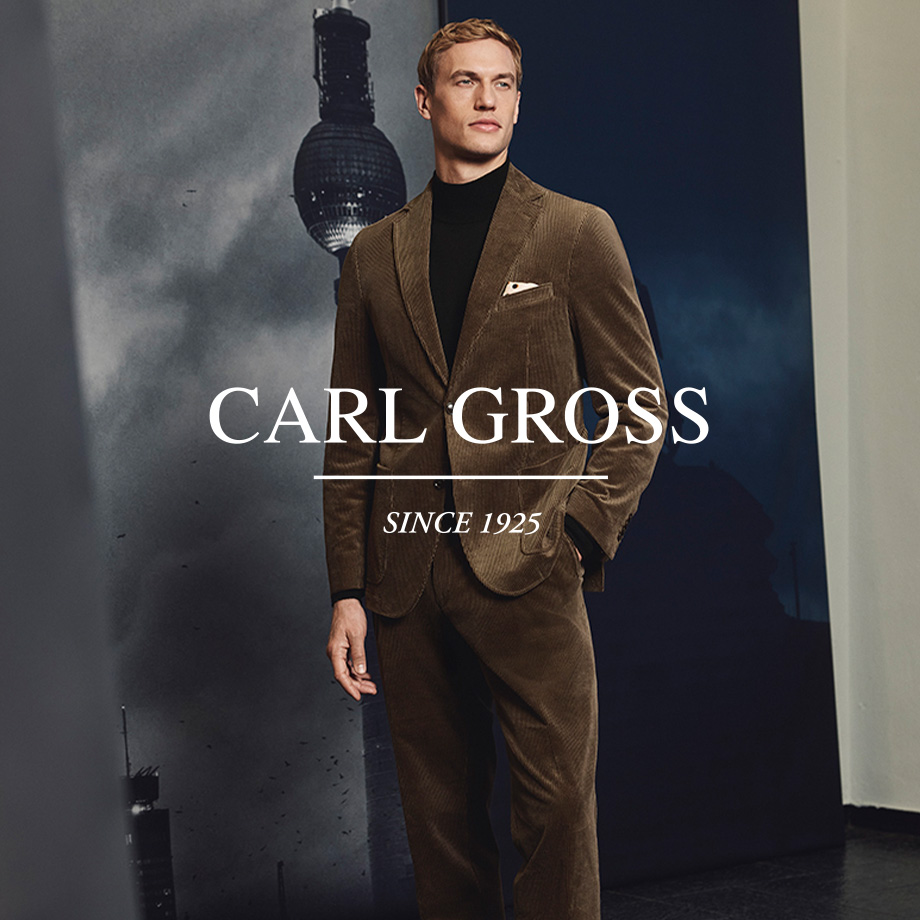 Mann in braunem Cord-Anzug mit schwarzem Rollkragenpullover und Einstecktuch