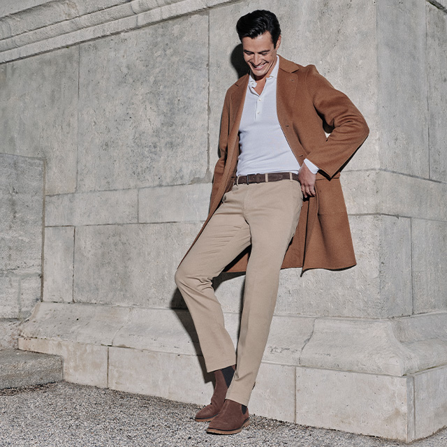 Mann in camelfarbenem Mantel mit beiger Chino und weißem Poloshirt, Business-Casual-Outfit