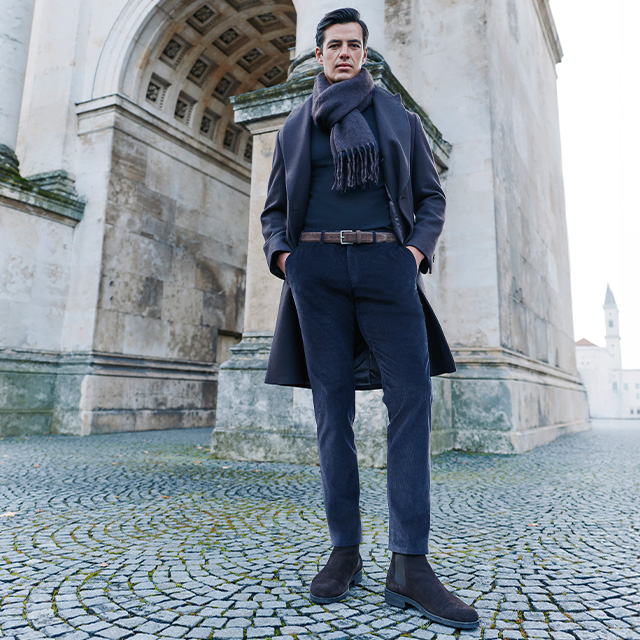 Mann in marineblauem Wollmantel mit Schal, Business-Outfit vor klassischer Architektur