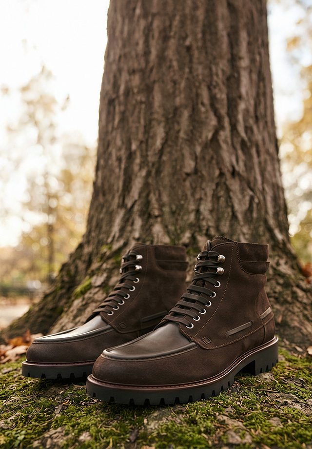 Braune Schnürstiefel aus Leder mit Profilsohle vor Baumstamm im Freien