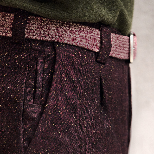 Elegante, dunkelviolette Hose mit melierter Textur und geflochtenem Gürtel, im Detailansicht getragen.